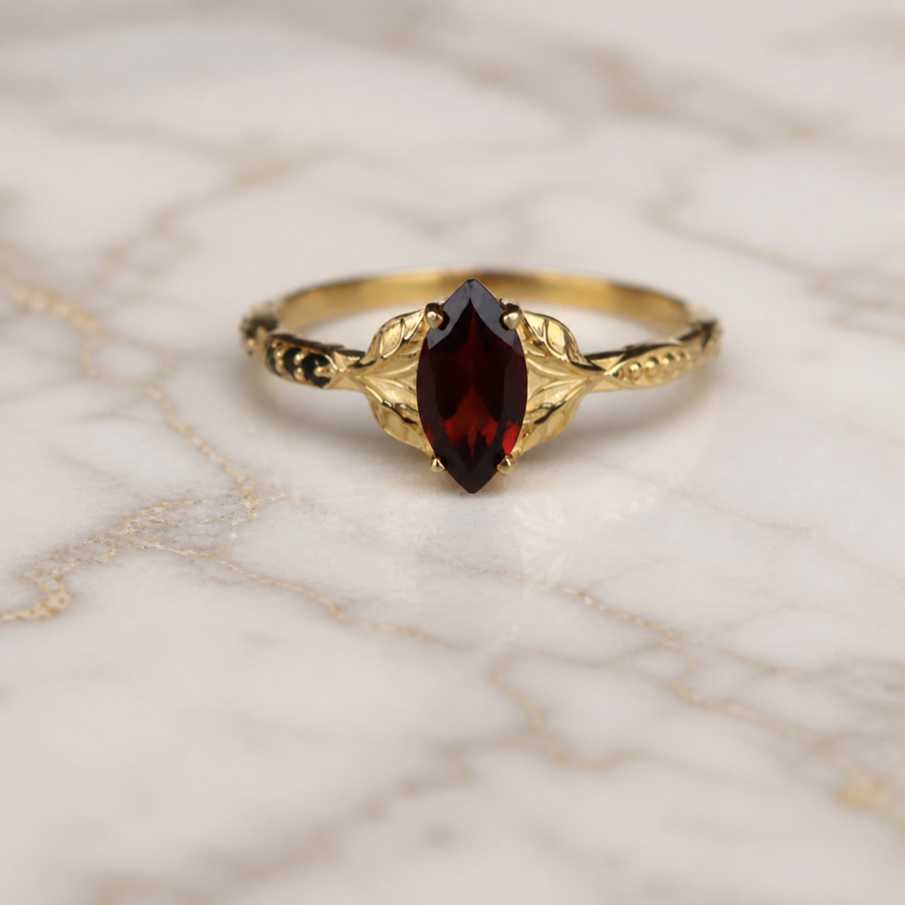 Colette marquise garnet leaf ring on polished Calacatta marble