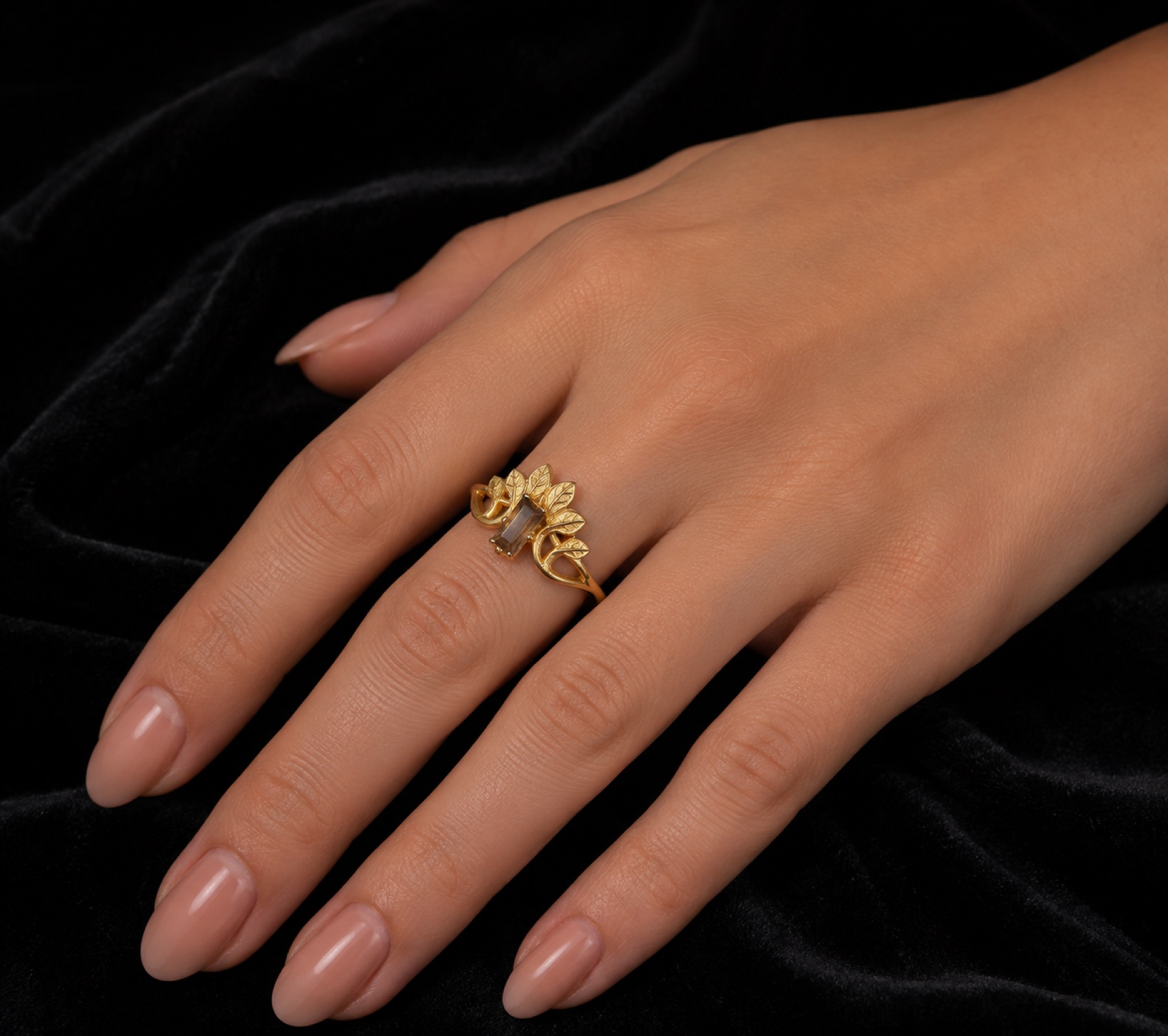 Fumée smoky quartz and gold leaf ring worn on a hand over black velvet
